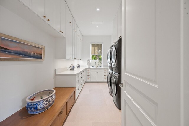 laundry area with stacked washing maching and dryer, sink, and cabinets