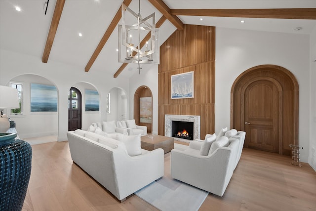 living room with a high end fireplace, light hardwood / wood-style flooring, high vaulted ceiling, beamed ceiling, and a chandelier