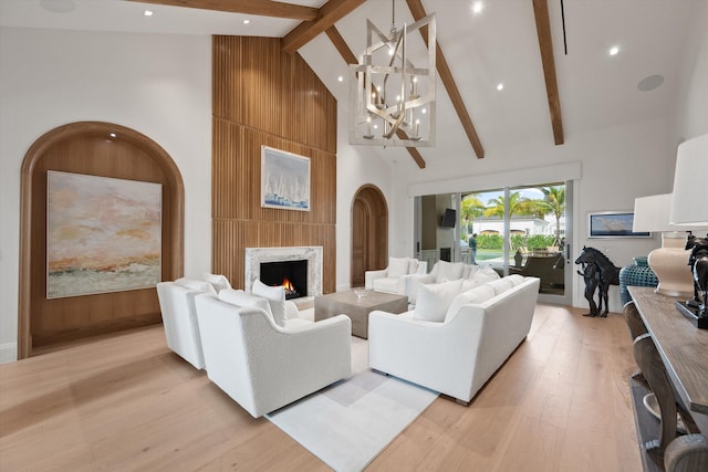 living room featuring a fireplace, high vaulted ceiling, light hardwood / wood-style floors, and beamed ceiling