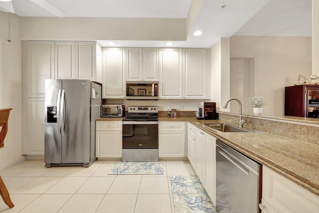 kitchen featuring sink, light tile patterned flooring, white cabinetry, appliances with stainless steel finishes, and light stone counters