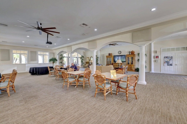 carpeted dining area with ornate columns, ornamental molding, and ceiling fan