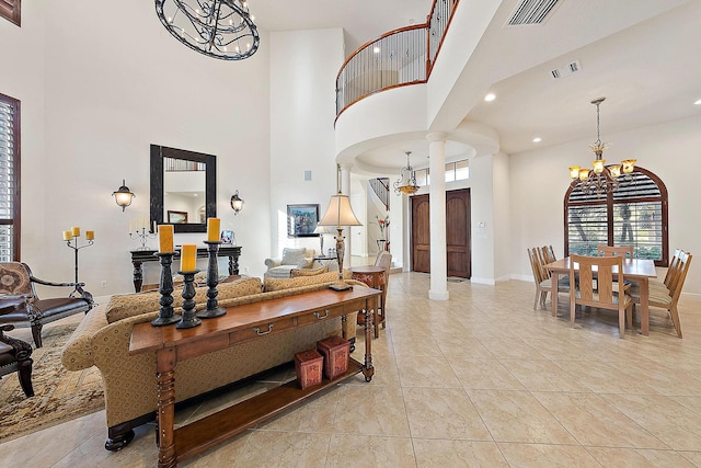 living room featuring an inviting chandelier, baseboards, visible vents, and ornate columns