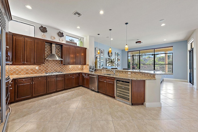 kitchen featuring pendant lighting, wall chimney range hood, stainless steel appliances, kitchen peninsula, and beverage cooler