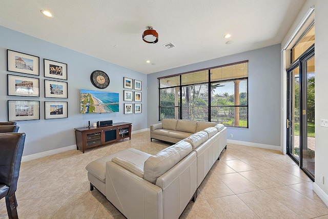 living room featuring light tile patterned floors, plenty of natural light, visible vents, and baseboards