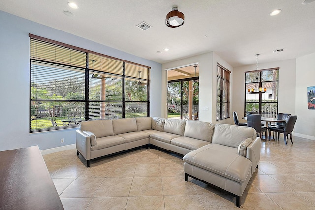 living area with visible vents, a notable chandelier, baseboards, and light tile patterned floors