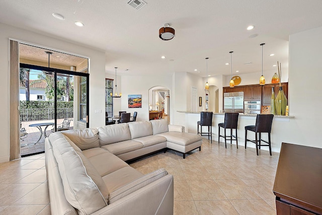 living area with arched walkways, light tile patterned floors, visible vents, and recessed lighting