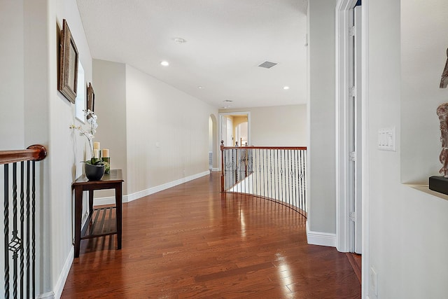 hallway featuring baseboards, visible vents, arched walkways, wood finished floors, and recessed lighting