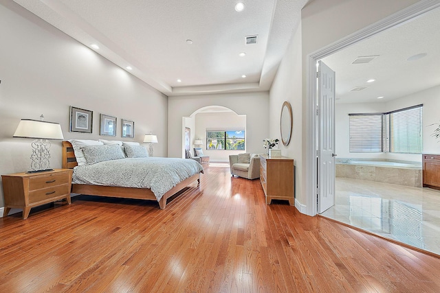 bedroom featuring light wood-style floors, arched walkways, visible vents, and recessed lighting