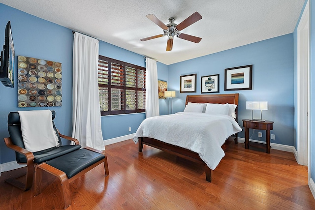 bedroom with ceiling fan, hardwood / wood-style floors, and a textured ceiling