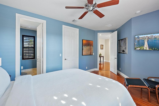 bedroom featuring a ceiling fan, baseboards, visible vents, and wood finished floors