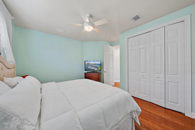 bedroom with ceiling fan, wood-type flooring, a closet, and a textured ceiling