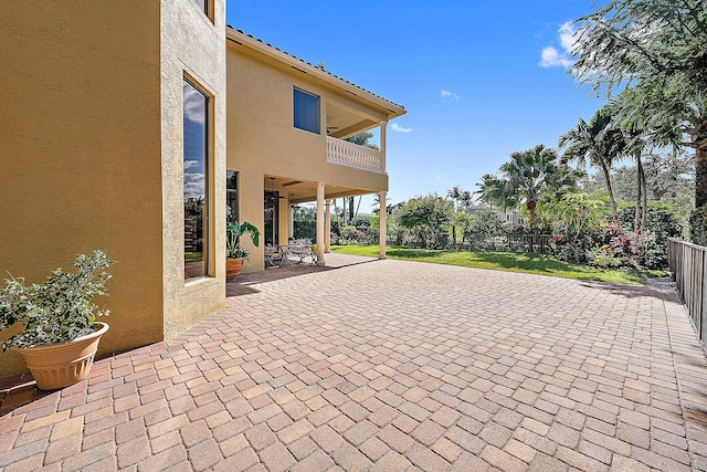 view of patio featuring a balcony and fence