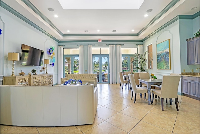 living area featuring light tile patterned floors, a skylight, french doors, a raised ceiling, and crown molding