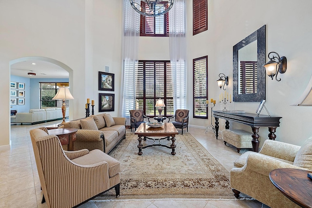 living room with arched walkways, a high ceiling, baseboards, and tile patterned floors