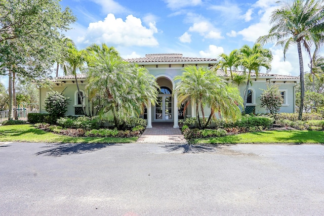 mediterranean / spanish-style home featuring french doors, a tile roof, and stucco siding