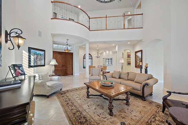 living area with light tile patterned floors, decorative columns, arched walkways, visible vents, and an inviting chandelier