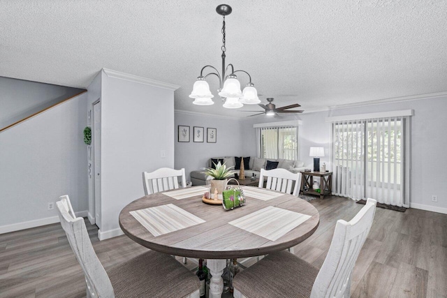 dining area with ceiling fan with notable chandelier, a textured ceiling, ornamental molding, and wood-type flooring