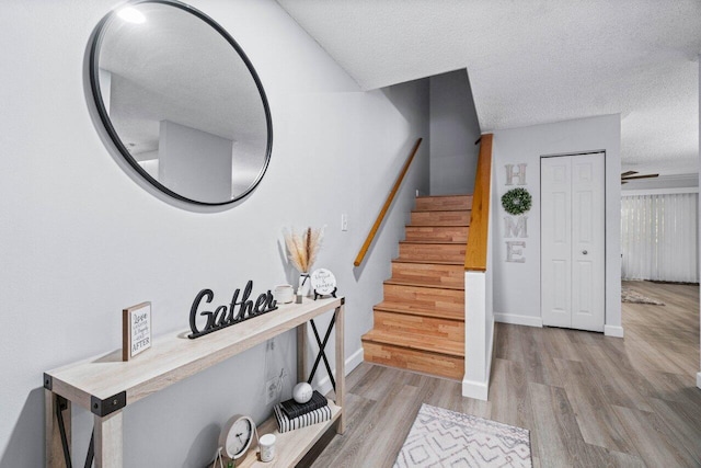 stairs featuring a textured ceiling and hardwood / wood-style flooring