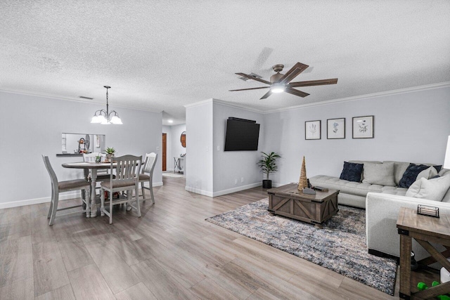 living room with ceiling fan with notable chandelier, a textured ceiling, ornamental molding, and light hardwood / wood-style flooring