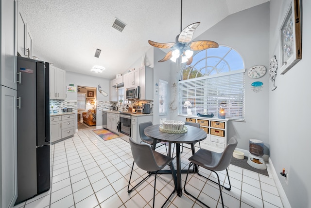 dining space featuring lofted ceiling, a textured ceiling, ceiling fan, and light tile patterned floors