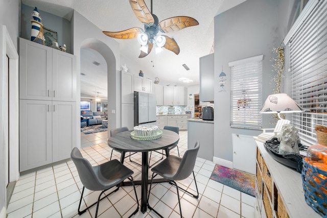 dining room with a textured ceiling, vaulted ceiling, and light tile patterned flooring