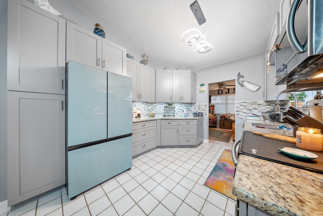 kitchen featuring a healthy amount of sunlight, refrigerator, decorative light fixtures, and a textured ceiling