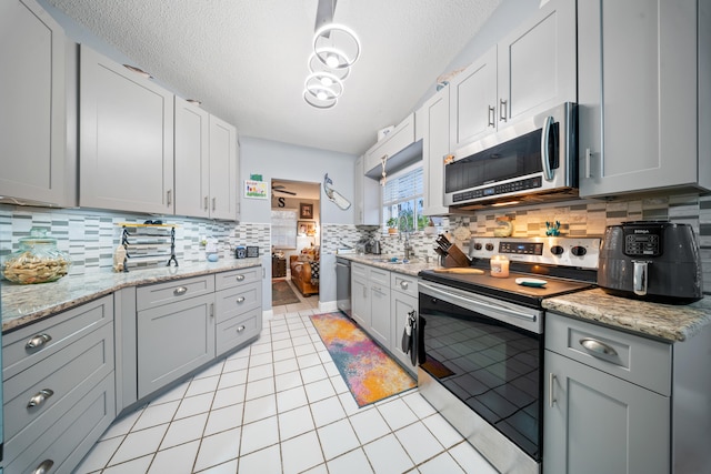 kitchen featuring a textured ceiling, stainless steel appliances, backsplash, and light tile patterned floors