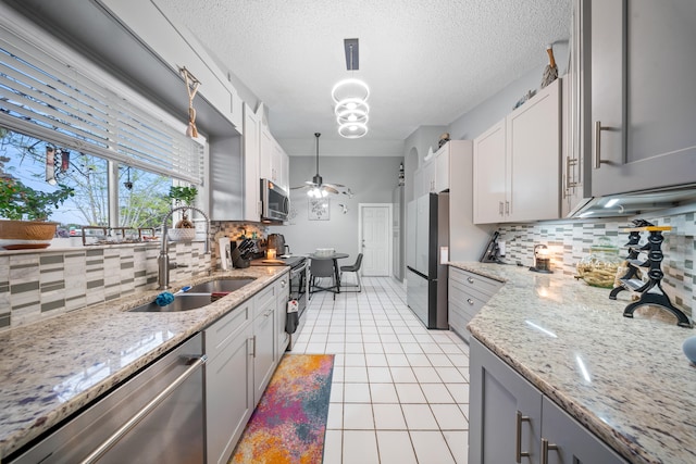 kitchen with sink, pendant lighting, appliances with stainless steel finishes, and decorative backsplash