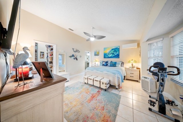 tiled bedroom with ceiling fan, a wall mounted air conditioner, vaulted ceiling, and a textured ceiling