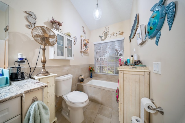 bathroom featuring toilet, vanity, tile patterned floors, and a relaxing tiled tub