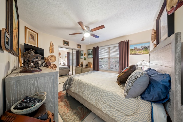 tiled bedroom with ceiling fan, a closet, and a textured ceiling