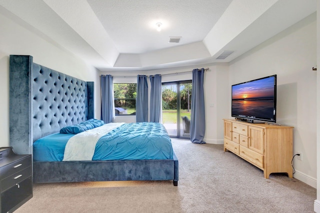 carpeted bedroom with access to exterior, a textured ceiling, and a raised ceiling