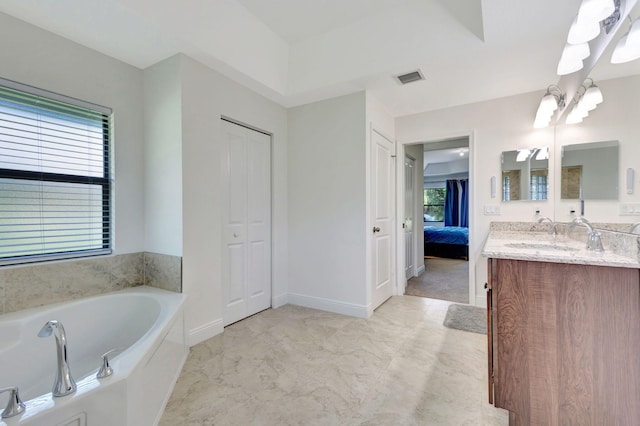 bathroom featuring tiled bath and vanity