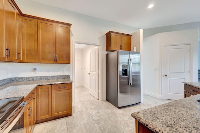 kitchen with light stone countertops, light tile patterned floors, and stainless steel appliances