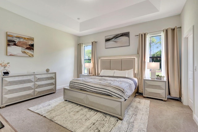 bedroom with a tray ceiling and light colored carpet