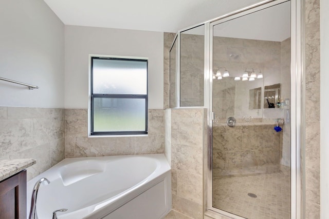 bathroom with separate shower and tub, vanity, and tile walls