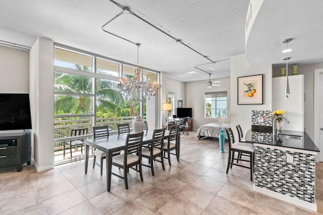 dining room with ceiling fan with notable chandelier, light tile patterned floors, and sink