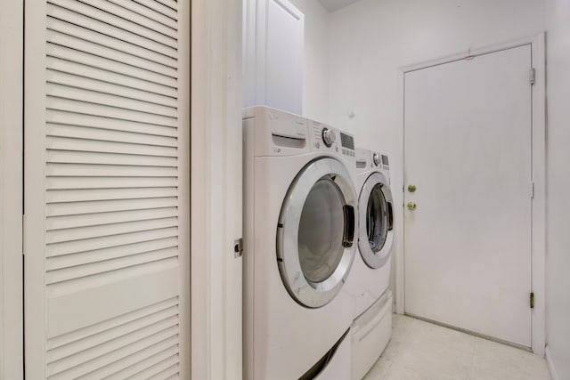 laundry room with laundry area, washer and dryer, and light tile patterned flooring