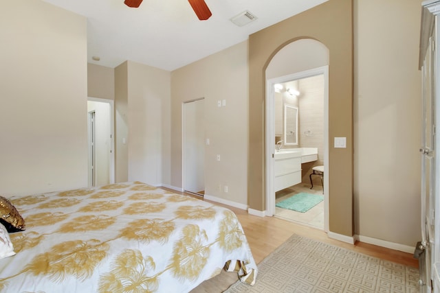 bedroom featuring visible vents, light wood-style flooring, a ceiling fan, connected bathroom, and baseboards