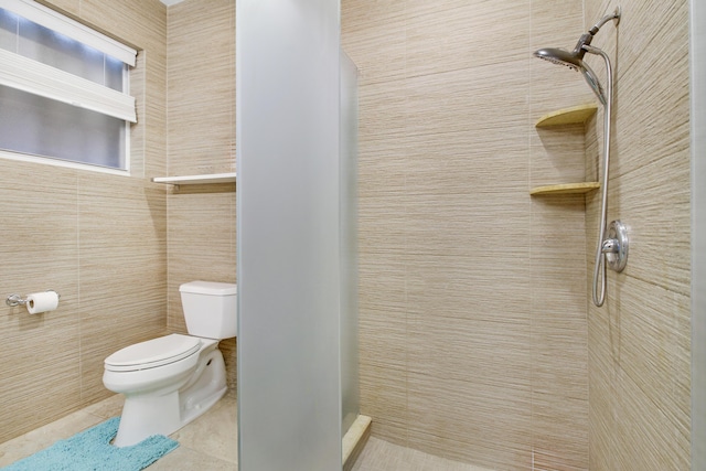 full bath featuring toilet, a stall shower, tile patterned flooring, and tile walls