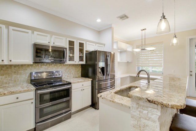 kitchen featuring a center island with sink, glass insert cabinets, appliances with stainless steel finishes, decorative light fixtures, and a sink