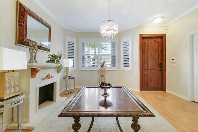 entrance foyer featuring crown molding, light wood-style flooring, a fireplace with flush hearth, a chandelier, and baseboards