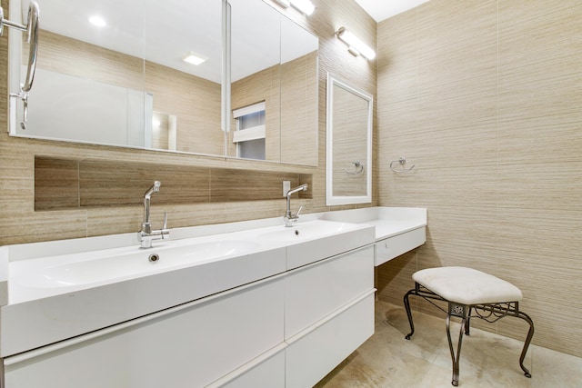 bathroom featuring a sink, double vanity, and tile walls