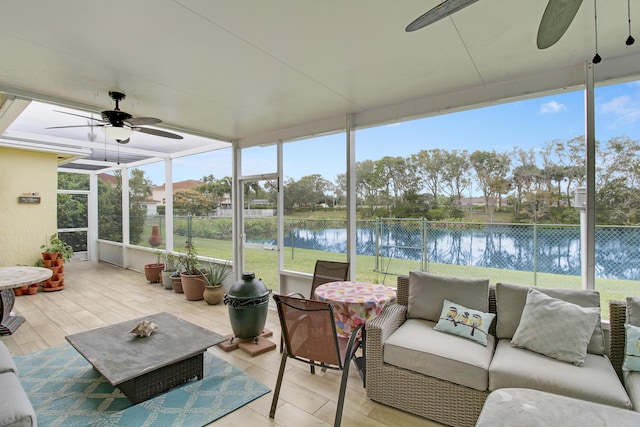 sunroom / solarium with ceiling fan and a water view