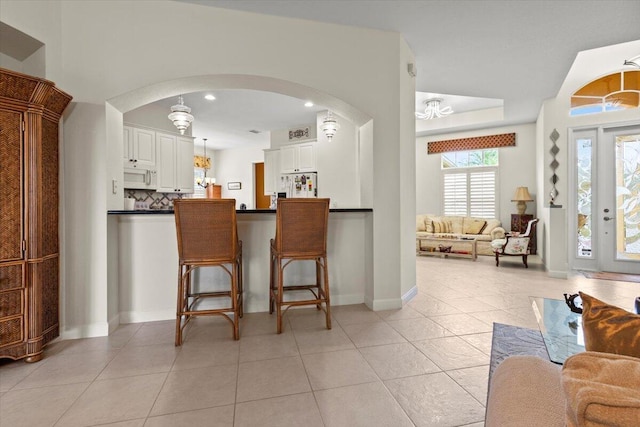 kitchen with pendant lighting, white appliances, light tile patterned floors, a notable chandelier, and white cabinetry