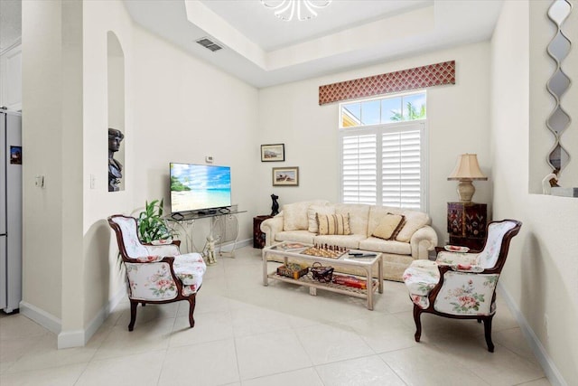 living room with light tile patterned floors and a raised ceiling