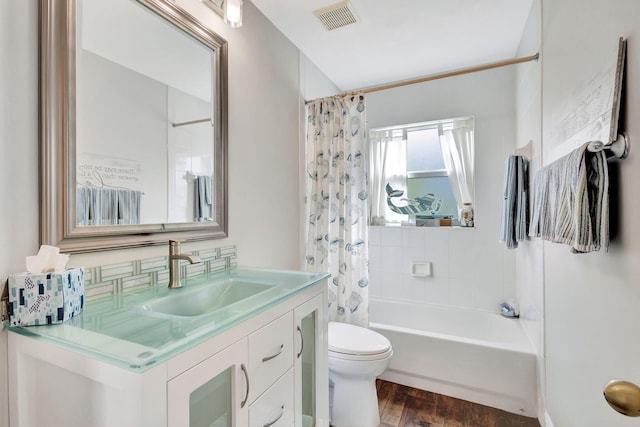 full bathroom featuring hardwood / wood-style floors, toilet, decorative backsplash, shower / tub combo with curtain, and vanity