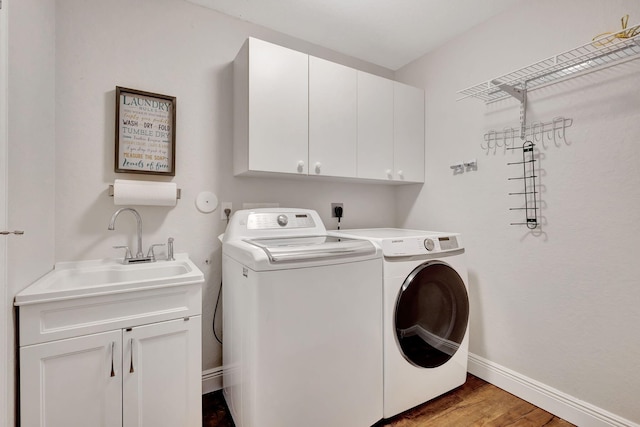 clothes washing area with washer and dryer, cabinets, wood-type flooring, and sink