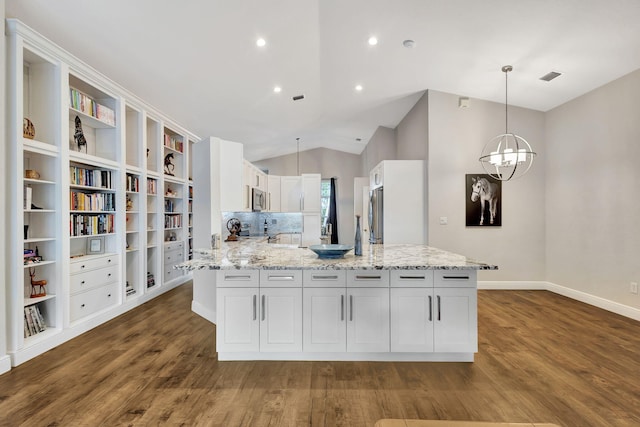 kitchen with light stone countertops, white cabinetry, stainless steel appliances, and vaulted ceiling