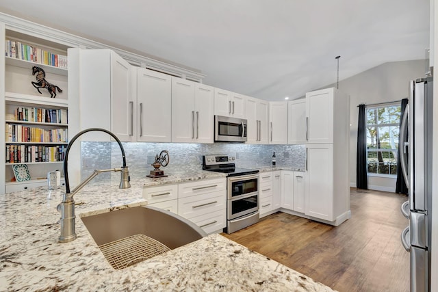 kitchen featuring light stone counters, stainless steel appliances, sink, light hardwood / wood-style flooring, and white cabinetry